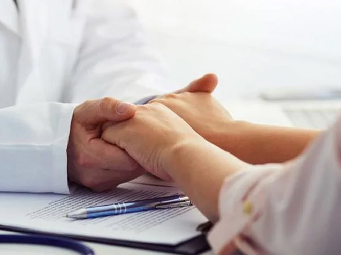 Lege holder hendene til pasient