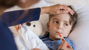 Gutt med feber som ligger i sengen