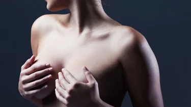 Kvinne holder seg på brystene