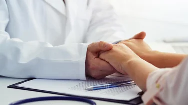 Lege som holder hendene til pasient