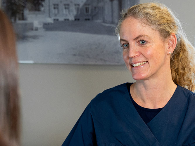 Gynekolog Tone R. Hafsteen i konsultasjon med mørkhåret kvinne.