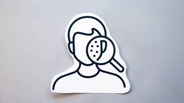 illustrasjon av et ansikt med noen prikker som sees gjennom et forstørrelsesglass.