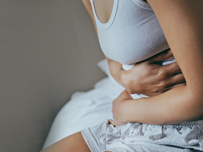 Nærbilde av en kvinne som holder seg til magen.