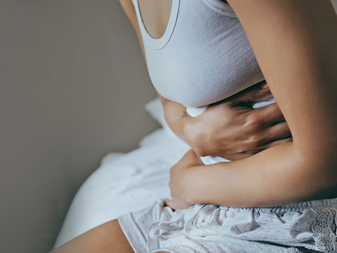 Nærbilde av en kvinne som holder seg til magen.