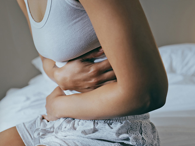 Nærbilde av en kvinne som holder seg til magen.