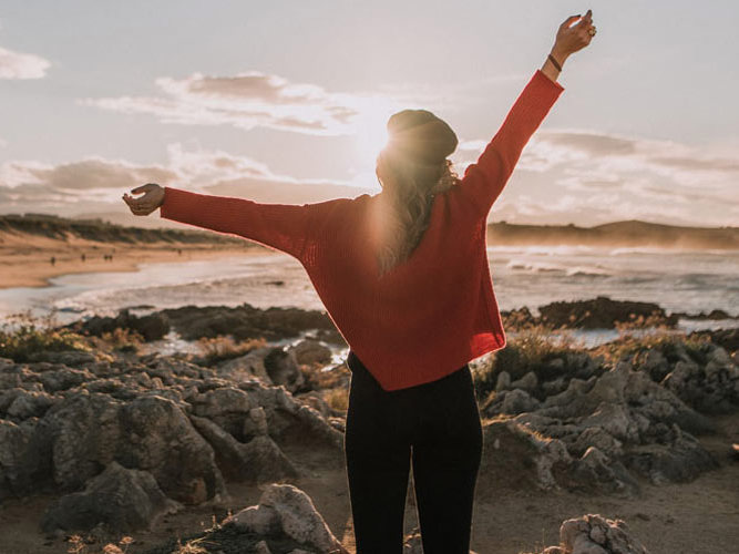 kvinne på utsiktspunkt med henda i været.