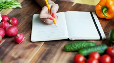 fargerik mat og en notatbok på en kjøkkenbenk.