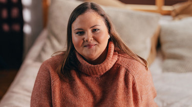 overvektig glad kvinne som sitter på sengen.